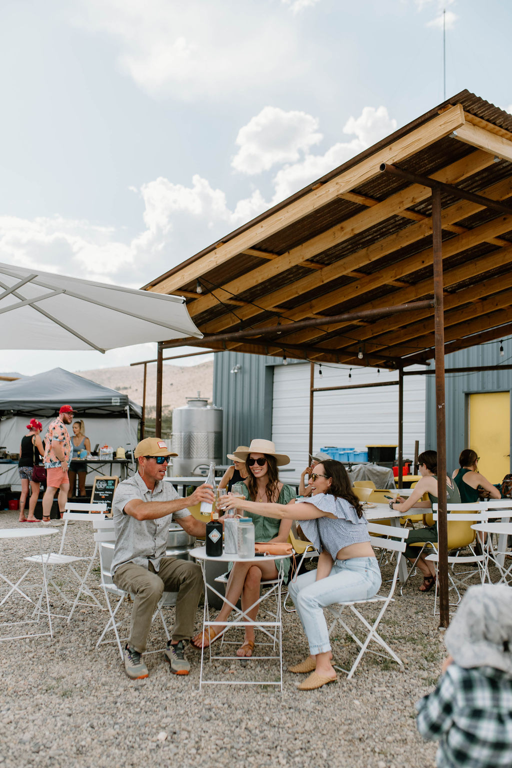 A group of young people underneath an outdoor tasting area enjoying a bottle of wine together at The Storm Cellar.